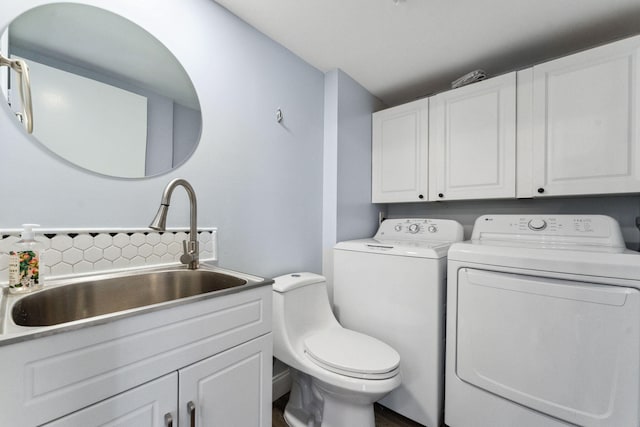 bathroom with tasteful backsplash, independent washer and dryer, and sink