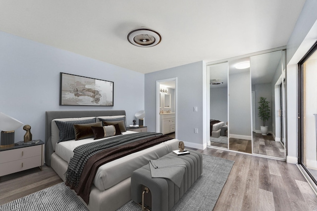 bedroom with hardwood / wood-style flooring, ensuite bath, and a closet