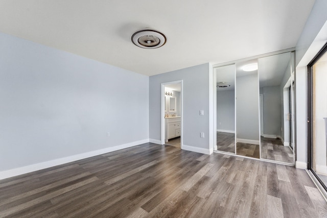 unfurnished bedroom featuring dark wood-type flooring, ensuite bathroom, and a closet