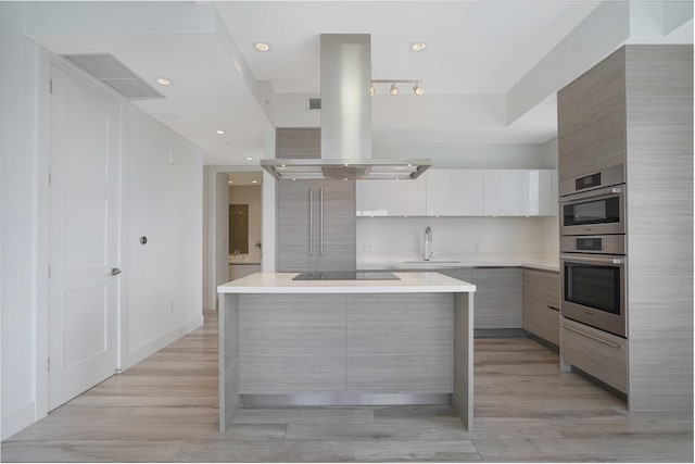 kitchen with sink, white cabinetry, a center island, black electric stovetop, and island range hood