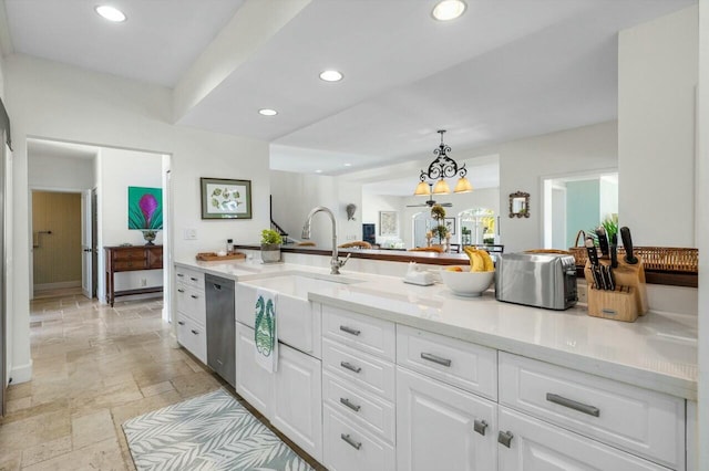 kitchen featuring white cabinets, pendant lighting, light stone counters, and stainless steel dishwasher