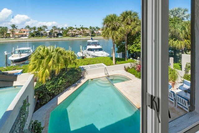 view of swimming pool with a patio, a water view, and a boat dock