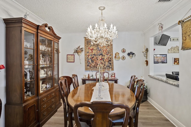 dining space featuring wood-type flooring, ornamental molding, a chandelier, and a textured ceiling