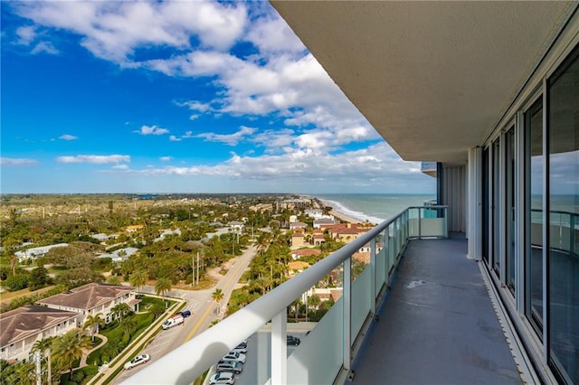 balcony with a water view and a view of the beach