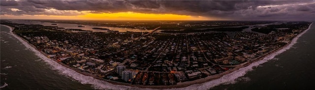 aerial view at dusk featuring a water view and a view of the beach