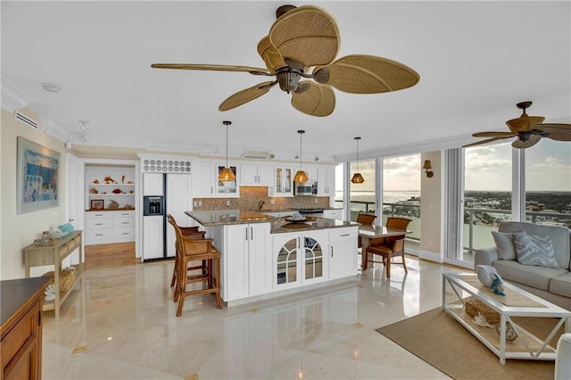 kitchen featuring a breakfast bar area, white cabinetry, a center island, paneled fridge, and decorative light fixtures