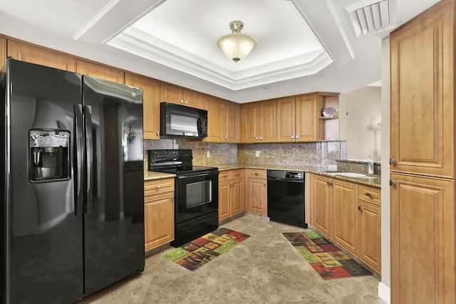 kitchen featuring sink, light stone counters, a tray ceiling, black appliances, and decorative backsplash