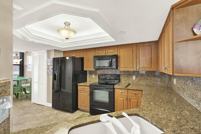 kitchen featuring stone countertops, black appliances, sink, decorative backsplash, and a tray ceiling