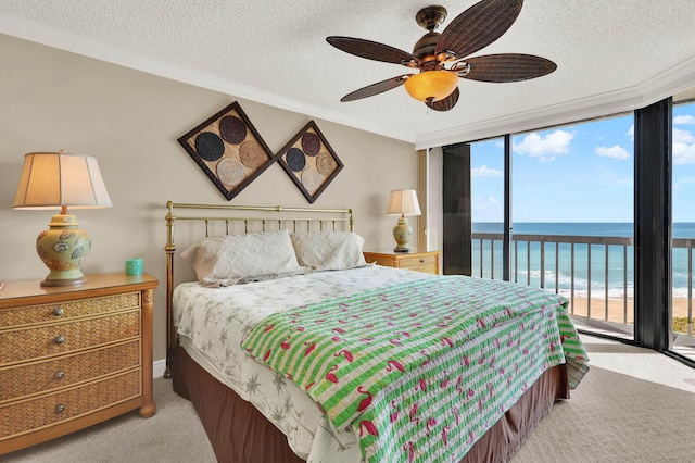 carpeted bedroom with a wall of windows, access to outside, ceiling fan, a water view, and a textured ceiling