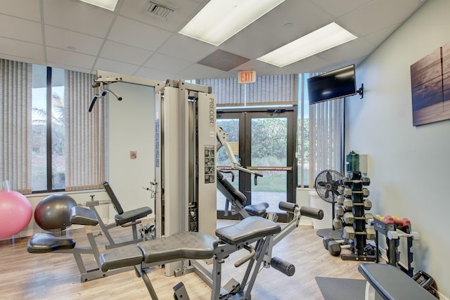 exercise room featuring hardwood / wood-style floors, a paneled ceiling, and french doors