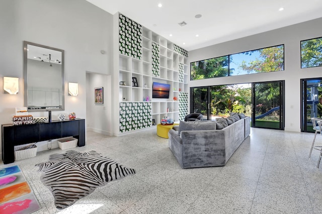 living area with a towering ceiling, visible vents, baseboards, and recessed lighting