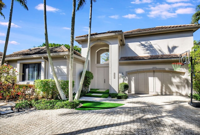 view of front of property featuring a garage, a tiled roof, decorative driveway, and stucco siding