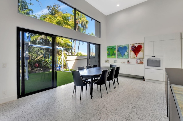 dining room with light speckled floor, recessed lighting, a towering ceiling, and baseboards