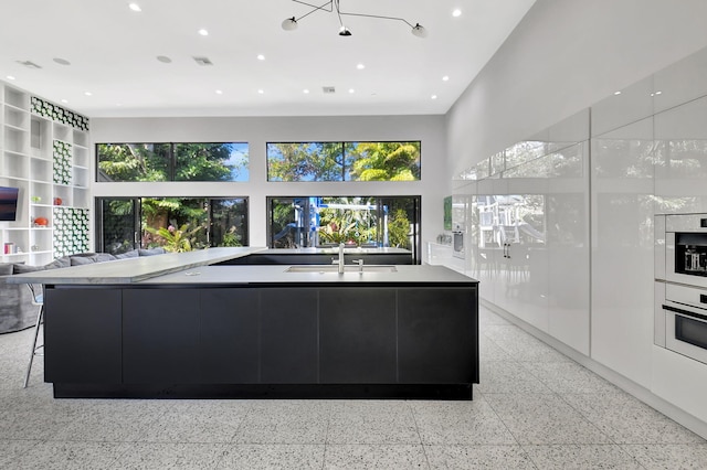 kitchen featuring a large island, modern cabinets, light countertops, light speckled floor, and a sink