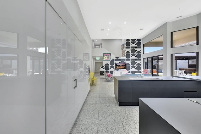 kitchen featuring modern cabinets, open floor plan, light countertops, light speckled floor, and a sink