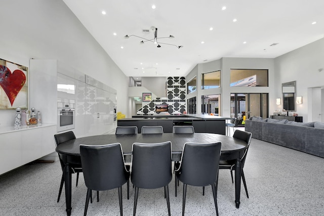 dining space featuring a high ceiling, light speckled floor, and recessed lighting