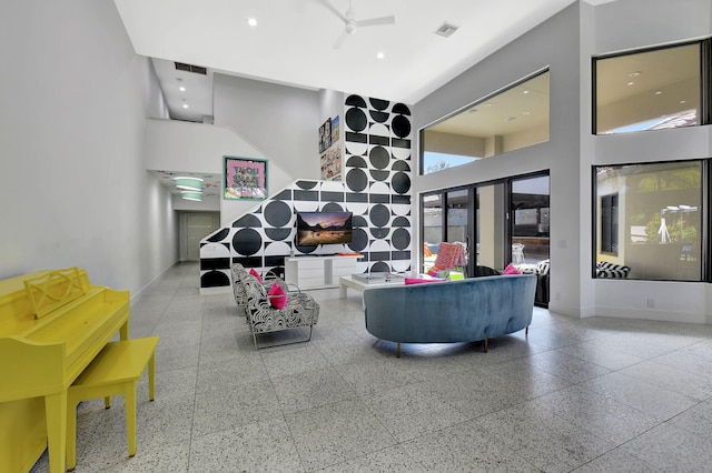 living room featuring a towering ceiling, baseboards, and visible vents