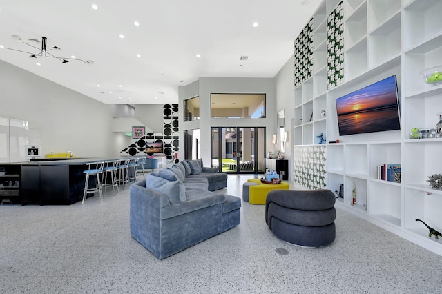 living area featuring speckled floor, recessed lighting, a towering ceiling, and built in features