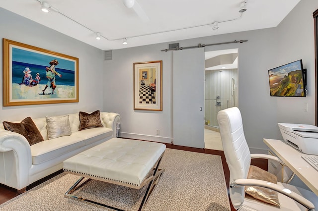 living room with baseboards, a barn door, visible vents, and track lighting