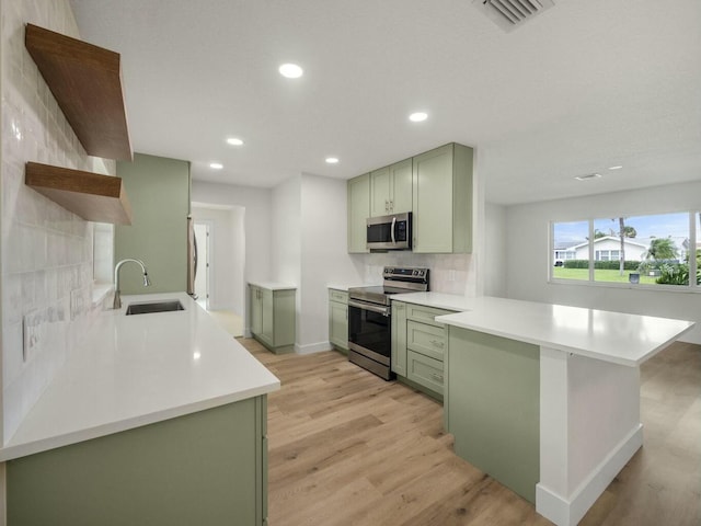 kitchen featuring visible vents, appliances with stainless steel finishes, a peninsula, light countertops, and green cabinets