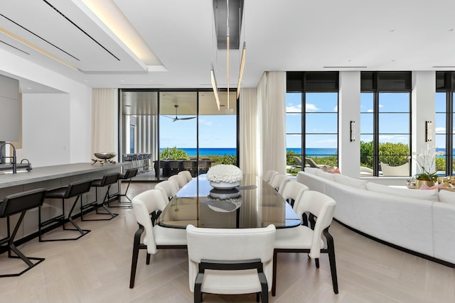 dining space featuring floor to ceiling windows, a water view, a healthy amount of sunlight, and sink