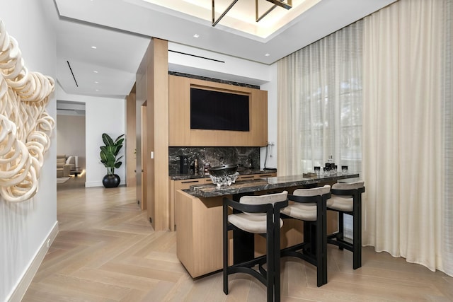 bar with light parquet floors, dark stone countertops, light brown cabinetry, and decorative backsplash