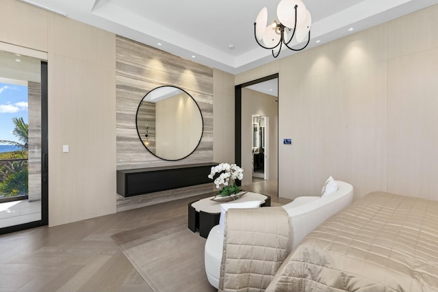 bedroom with an inviting chandelier, parquet flooring, and a raised ceiling