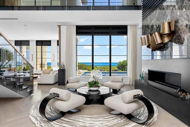 interior space featuring parquet flooring, a towering ceiling, and a water view