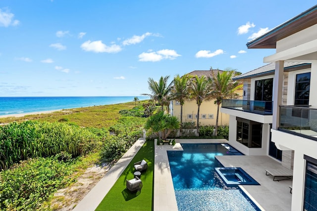 view of swimming pool with an in ground hot tub, a water view, a beach view, and a patio