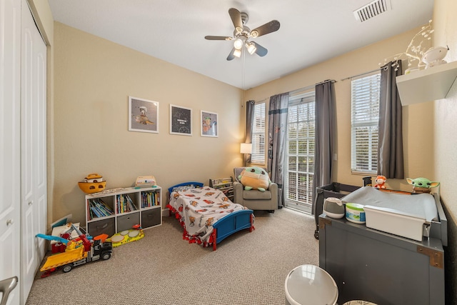 carpeted bedroom with access to exterior, a closet, visible vents, and a ceiling fan