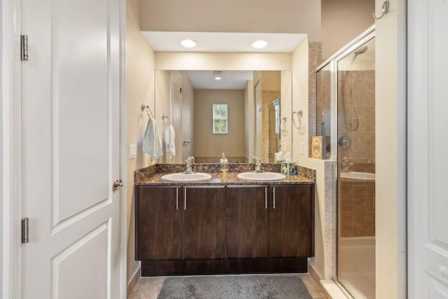 bathroom with double vanity, a stall shower, and a sink