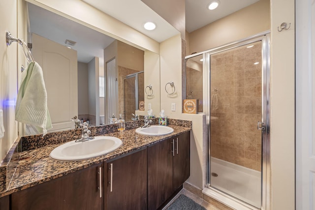 full bathroom featuring double vanity, a stall shower, a sink, and recessed lighting