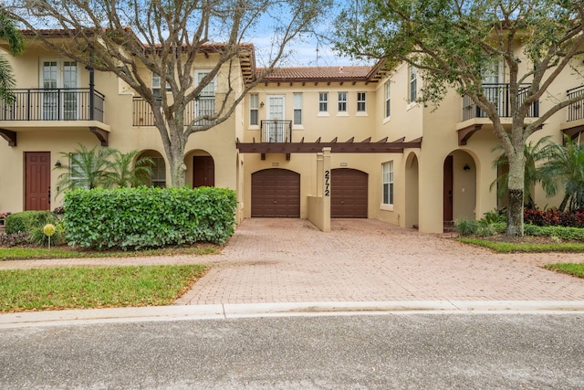 view of front of home featuring a garage, driveway, a tiled roof, and stucco siding