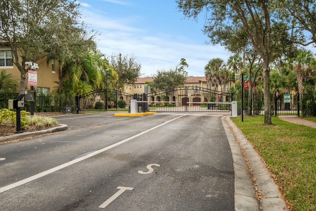 view of street with traffic signs, a gate, curbs, and a gated entry