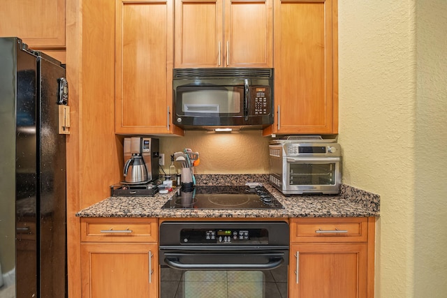 kitchen with black appliances, a toaster, dark stone countertops, and a textured wall