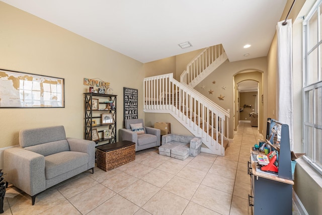 living room featuring light tile patterned floors, stairs, arched walkways, and recessed lighting