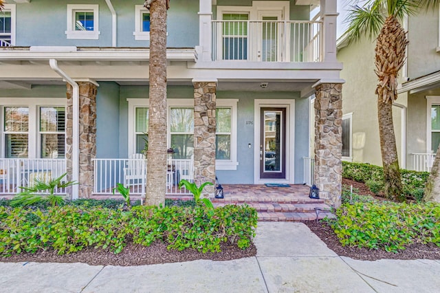 entrance to property featuring a porch and a balcony