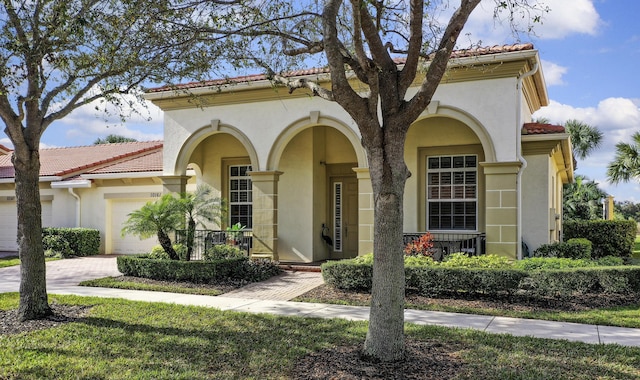 mediterranean / spanish house featuring driveway, an attached garage, covered porch, stucco siding, and a tile roof