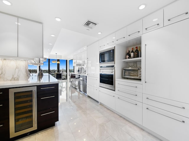 kitchen with white cabinetry, stainless steel oven, wine cooler, and decorative light fixtures