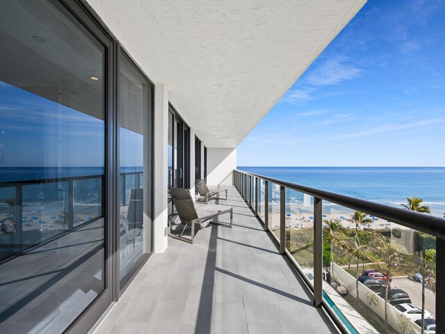 balcony featuring a water view and a beach view