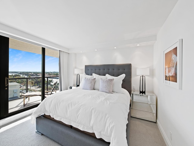 bedroom with carpet floors, a wall of windows, and access to outside