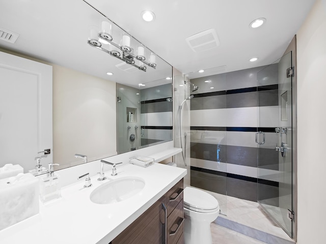 bathroom featuring vanity, a shower with shower door, and toilet