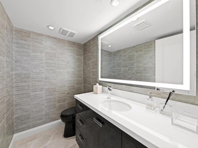 bathroom with vanity, tile patterned flooring, tile walls, and toilet