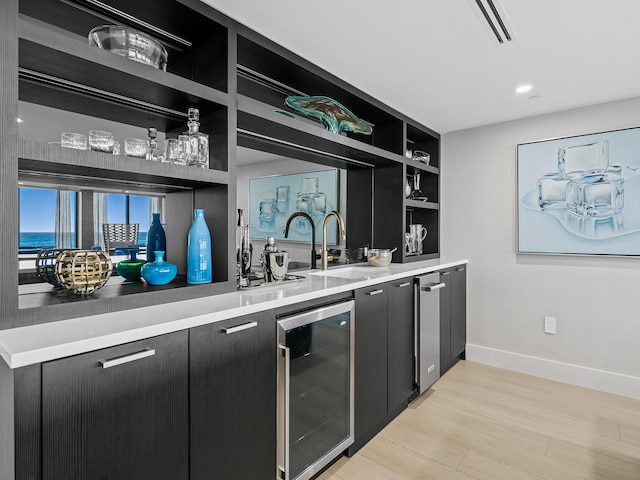 bar with wine cooler, light hardwood / wood-style flooring, sink, and built in features