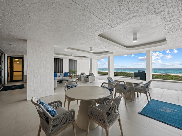 view of patio / terrace with a water view, outdoor lounge area, and a view of the beach