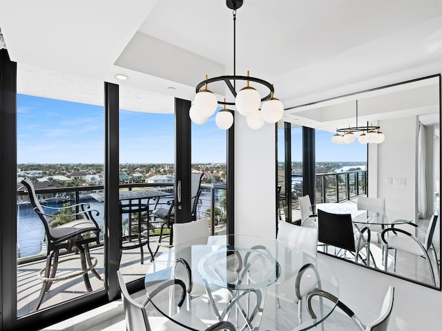 dining room featuring a wall of windows, a water view, and a notable chandelier