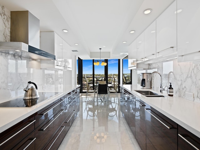 kitchen featuring sink, white cabinetry, dishwasher, wall chimney exhaust hood, and hanging light fixtures