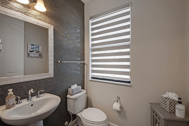 bathroom featuring a sink, backsplash, and toilet