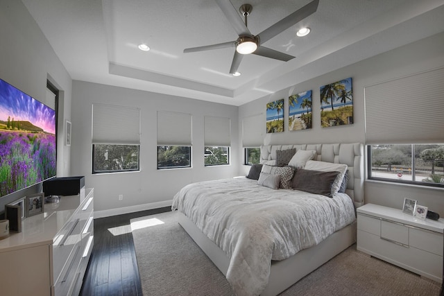 bedroom featuring ceiling fan, hardwood / wood-style flooring, recessed lighting, baseboards, and a raised ceiling