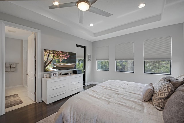 bedroom with multiple windows, baseboards, a raised ceiling, and wood finished floors